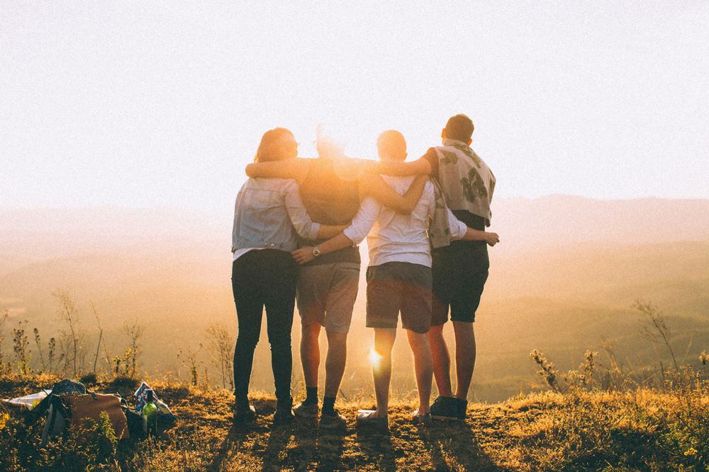 A group of 4 friends hugging,representing the decision between solo travel or group travel