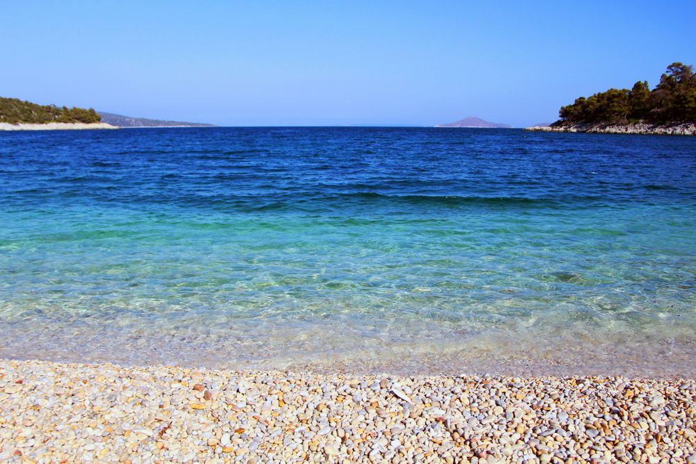 Uma praia em Alonissos, Grécia nos 5 Lugares Calmos para Passar o Verão na Europa