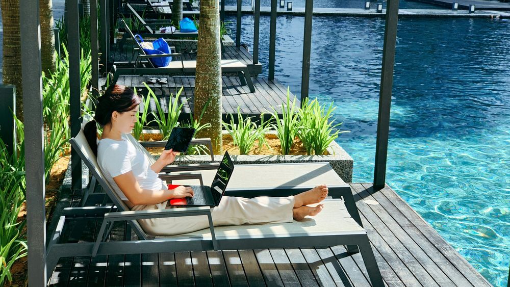 Woman working by the pool representing Digital Nomad Visas in the 20 Travel Trends for 2025