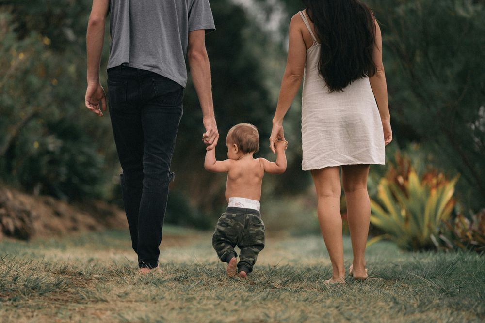 Two parents holding hands with a baby in the Tips for Traveling with Young Children