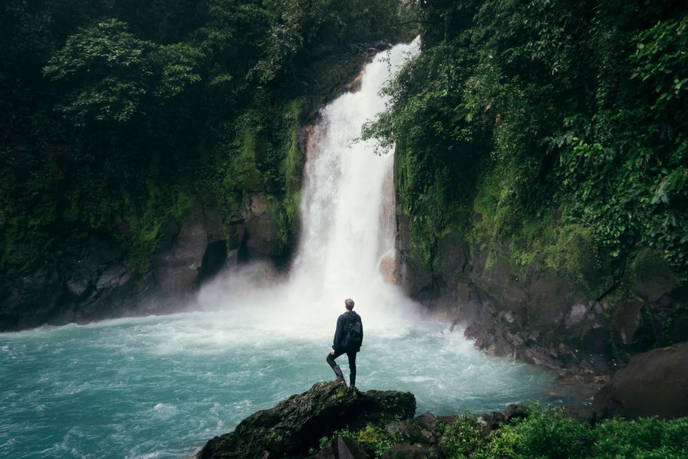 Travel Planning with the Help of AI, a man in looking at a waterfall