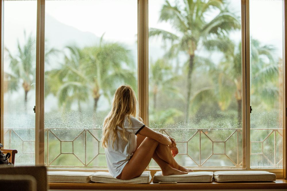 Woman looking out the window representing Wellness Getaways for Mind and Body in the 20 Travel Trends for 2025