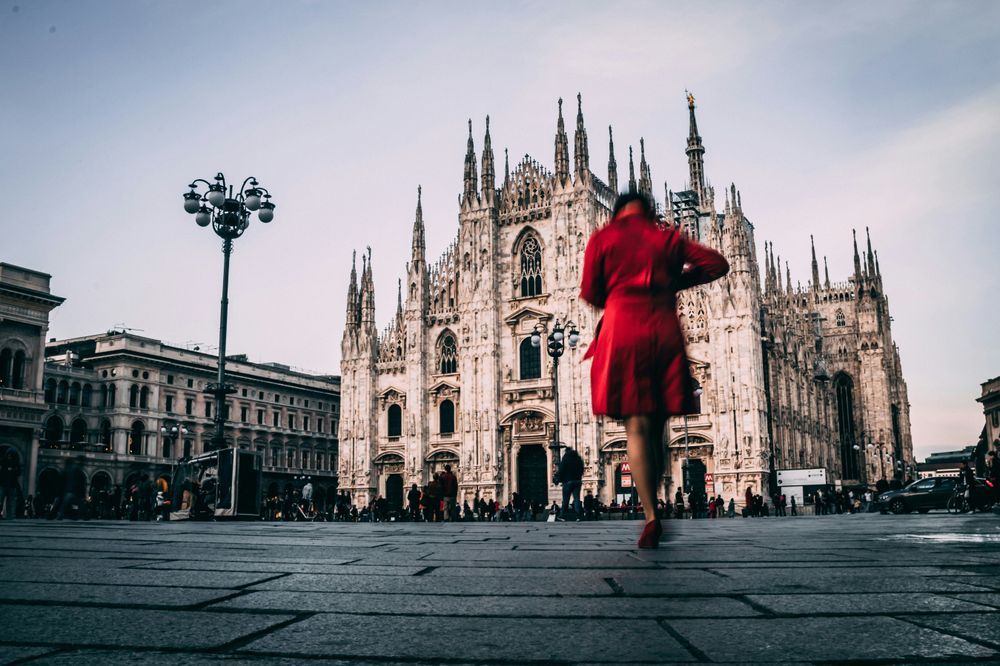 A woman with a red coat in front of the Duomo in What to Visit in Milan