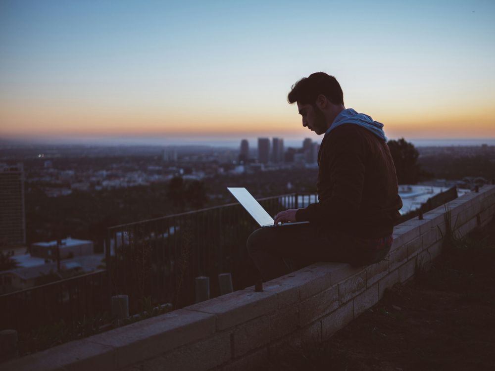 Man on top of a roof looking at a computer, representing Business Trip Planning