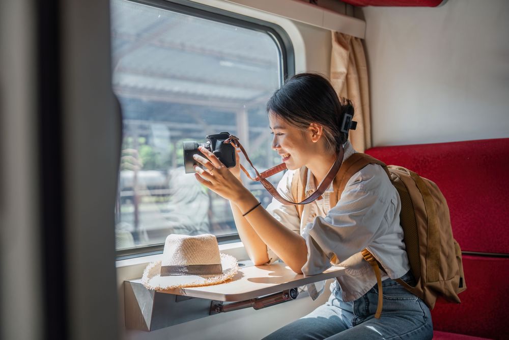 Una donna asiatica su un treno con una fotocamera che viaggia a tempo pieno