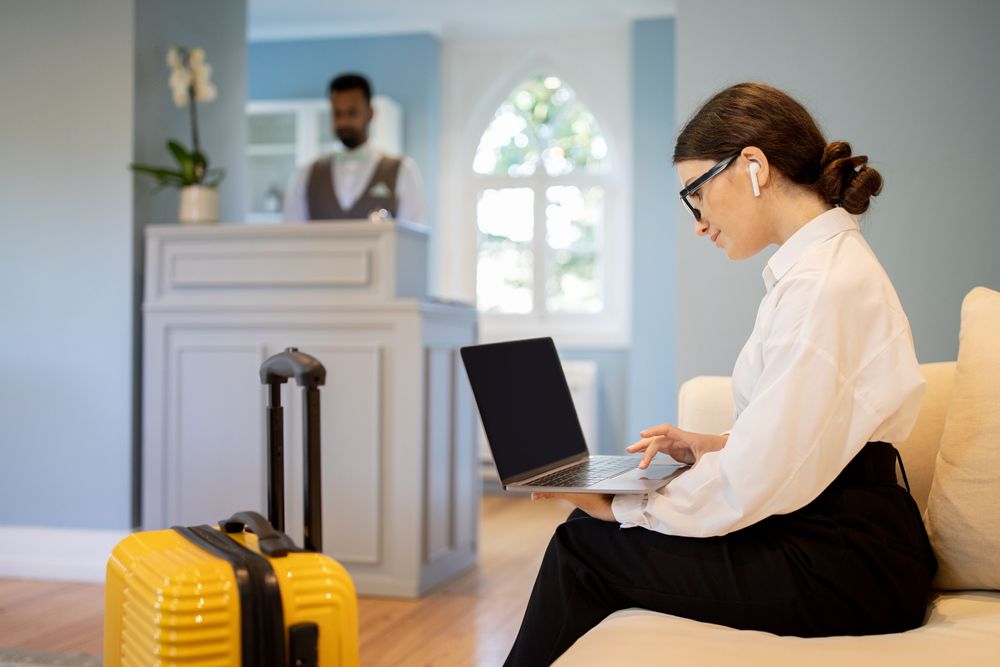 Tips voor het boeken van betaalbare accommodatie, vrouw zittend op een bank kijkend naar een computer