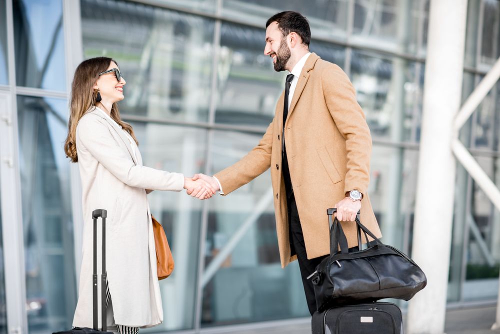 Two people meeting and shaking hands, representing Business Trip Planning