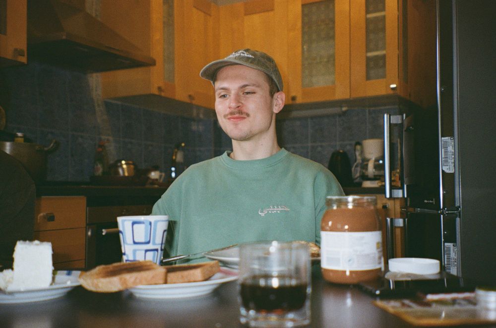 A man enjoying breakfast in a hostel kitchen representing  The Best Money Saving Travel Hacks to Have in 2025