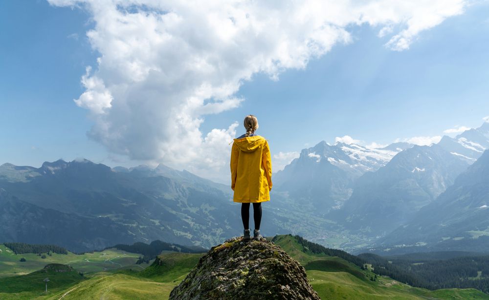 Person standing on a rock looking at the landscape representing Budget Travel Tips