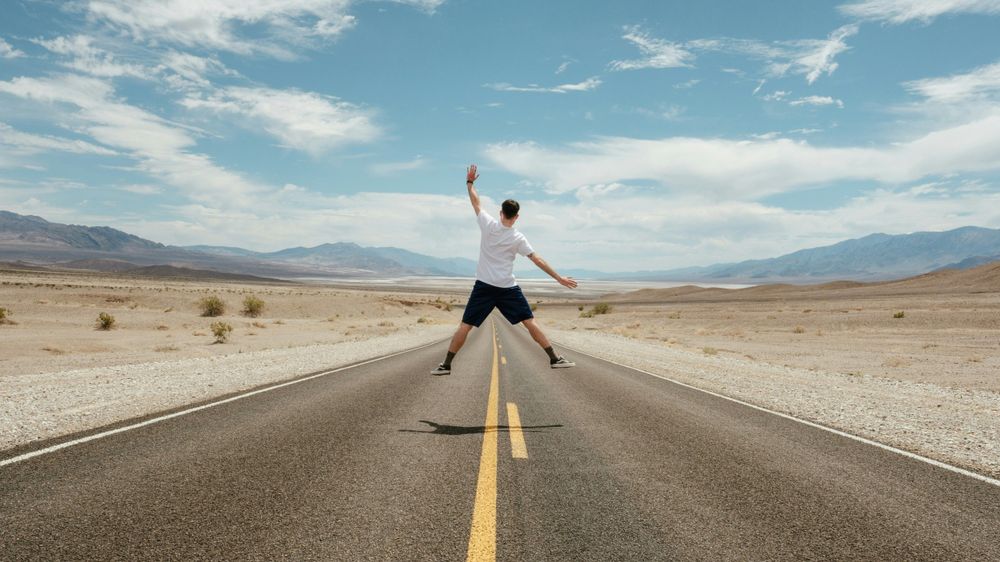 Man jumping on the middle of the road, representing Budget Travel Tips