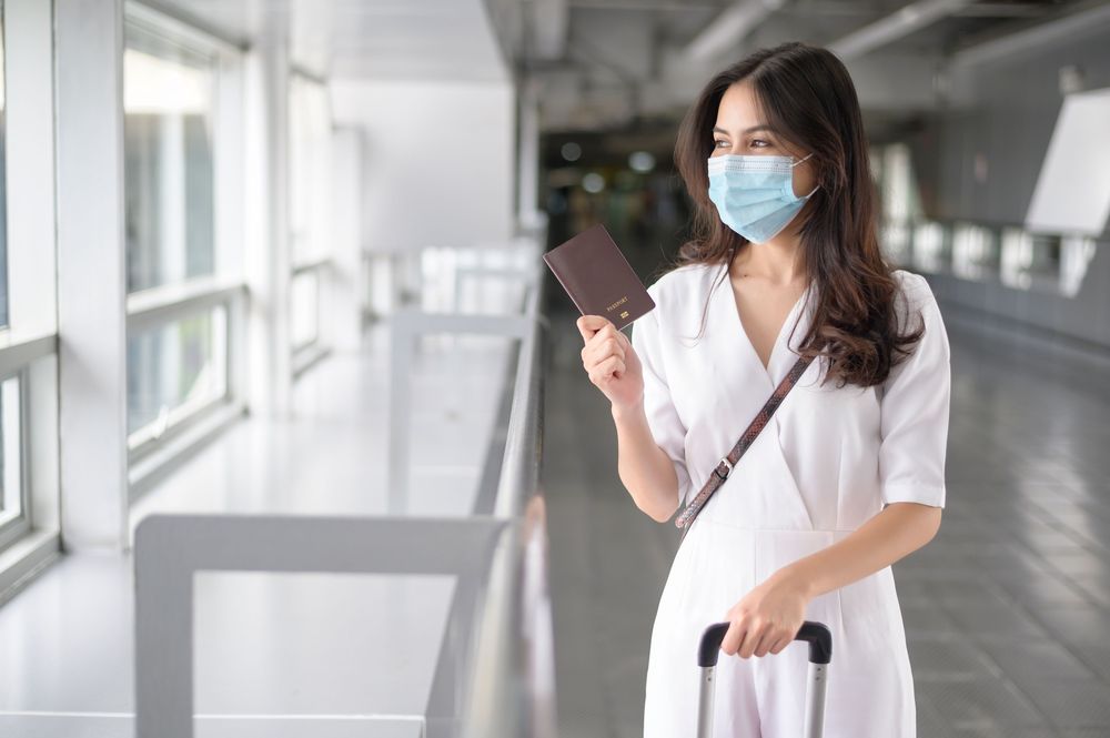 Woman in an airport wearing a face mask as a travel safety advice