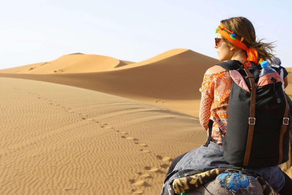 woman in the desert, representing 10 Travel Essentials You Need On Every Trip