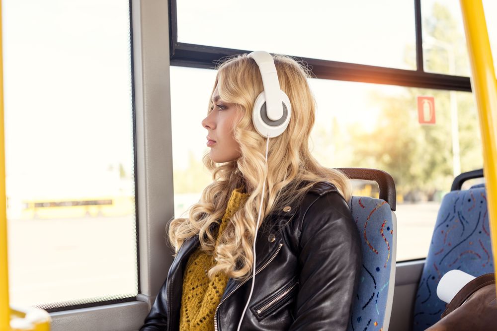 Mujer Joven Usando Auriculares representando La Guía Definitiva del Equipo de Viaje en Solitario