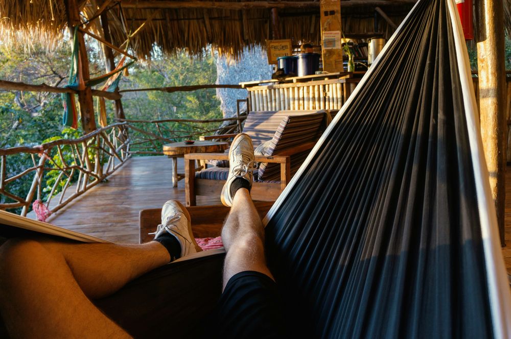 Man laying on a hammock, representing low budget accommodation and Hacks to Save Money while traveling