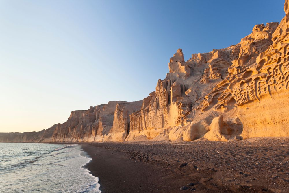 Dark sand beach, representing the best cheap activities in Santorini