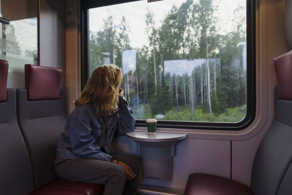 Girl looking outside a train window in representation of How to Plan a Last Minute Trip:
