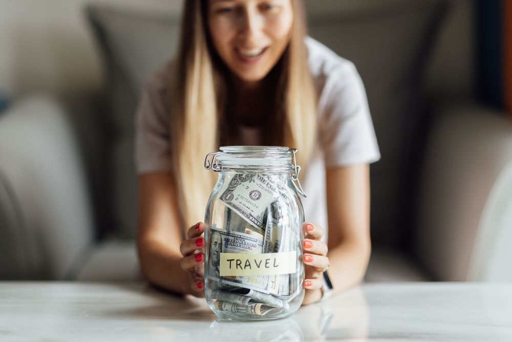 Woman with a savings jar, representing how to create a travel budget